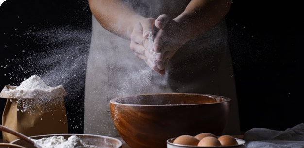 Chef's hands dusting flour while preparing dough