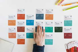 Hand arranging color-coded content planning cards on a wall