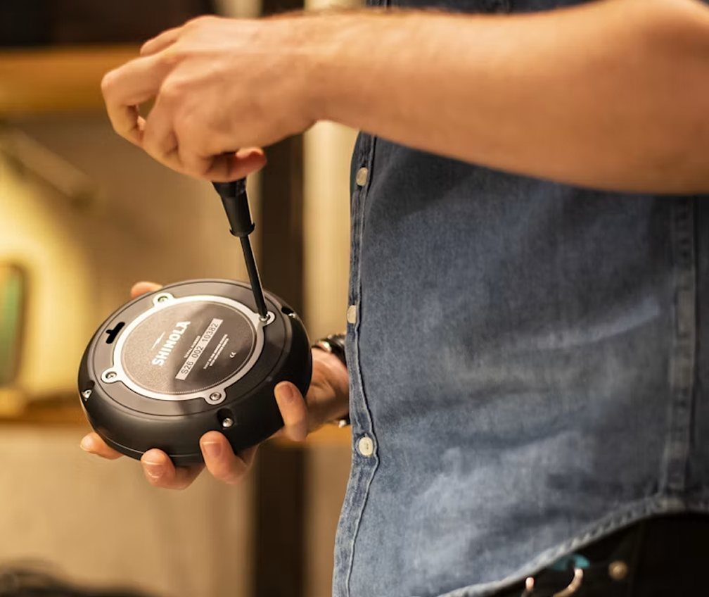 Technician repairing a Shinola audio device with a screwdriver