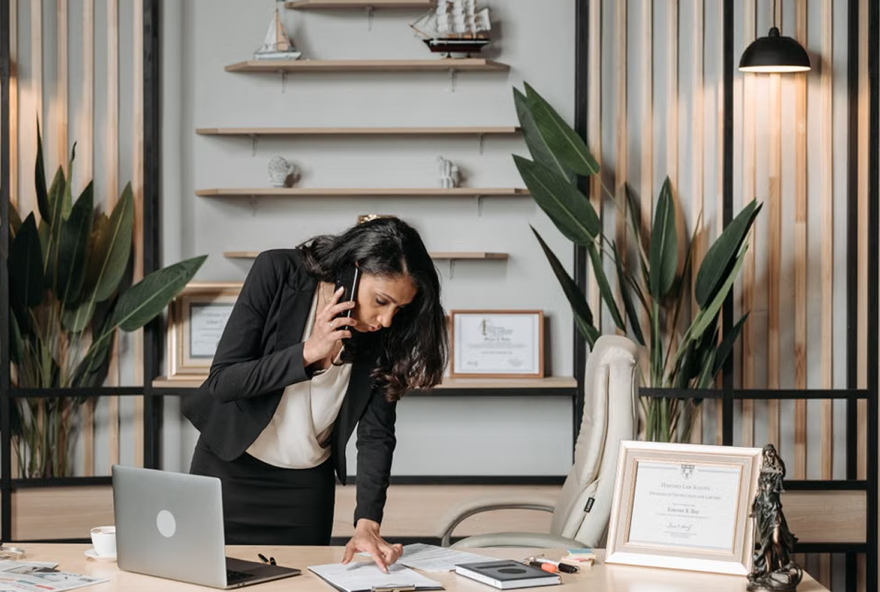 Attorney on a phone call at her desk, with law degree credentials displayed behind her