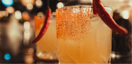 Craft cocktails with a chili-rimmed glass on a restaurant table