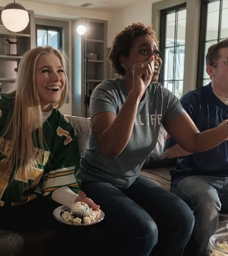 Friends reacting excitedly while watching a game together on TV